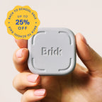 A hand holding a small gray square electronic brick with the word 'Brick' embossed on the front, against a light beige background, with a yellow promotional badge reading 'Back to School Sale Up to 25% Off'.
