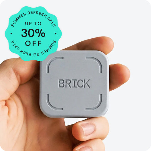 Hand holding a gray 'BRICK' device with a summer refresh sale badge on a white background