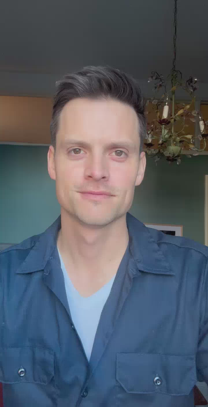 man in a room with a chandelier behind him